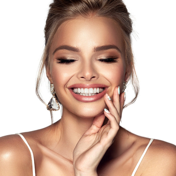 Woman with a bright smile, wearing earrings and a white top against a light background